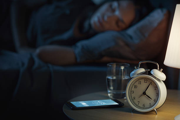 istock Woman sleeping and alarm ringing on her smartphone 2204495230