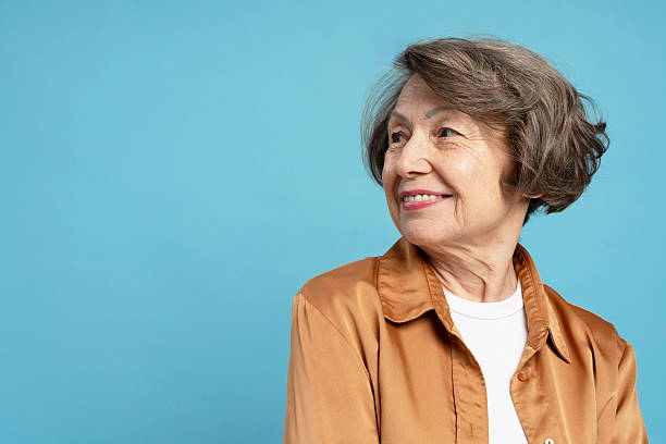 istock Smiling senior woman looking away on blue background 2204495711