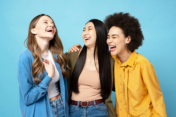 istock Three young women laughing together on blue background 2204495752