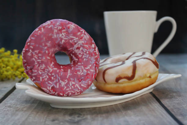 istock Delicious glazed donuts with sprinkles on a white plate. 2204500250