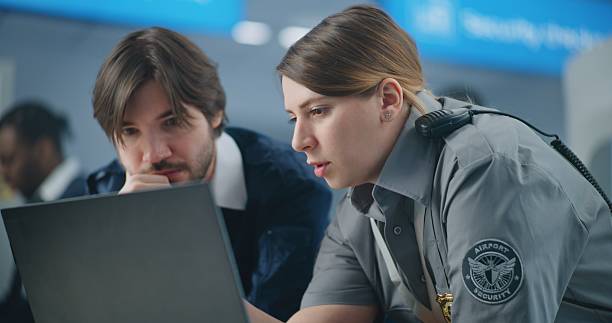 istock Airport Security Checkpoint: Close Up of Two Diverse Security Officers Using Laptop and Talking 2204501560