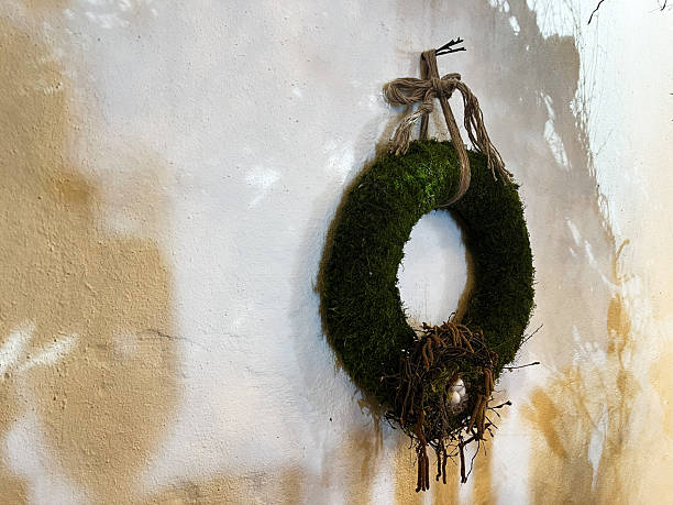 Decorative moss wreath with nest hung on rustic textured wall by twine