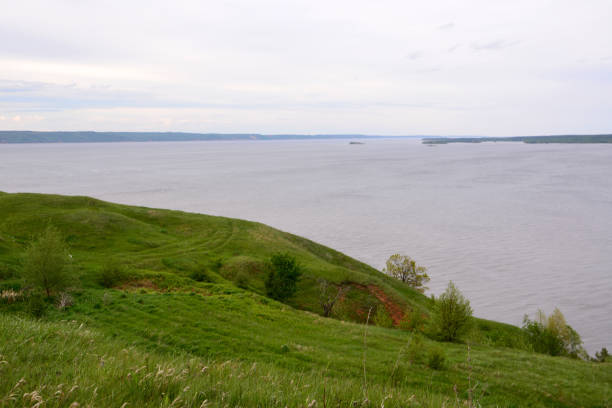 istock Scenic view of a river and green hills under a cloudy sky 2204502677