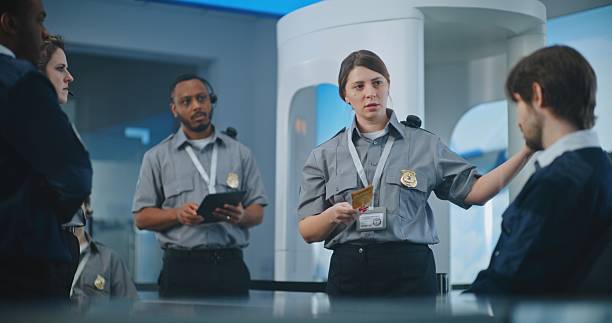istock Female Security Officer Holding Boarding Pass, Explaining Procedures to Team of Workers 2204502742
