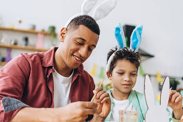 istock Father and son painting easter bunny decorations wearing bunny ears headband 2204502906