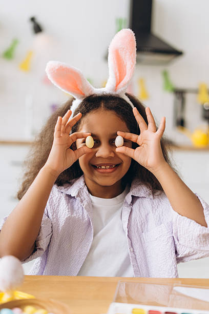 istock Smiling girl holding easter eggs and wearing bunny ears headband 2204502912