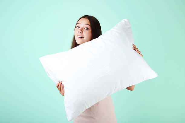 istock Young girl with white pillow on mint background 2204503573