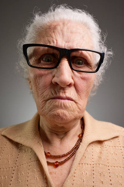 A deaf old woman frowns, cupping her ear in an effort to hear something being said.