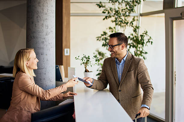 Professional Businessman Requesting Service from Receptionist at an Office Front Desk stock photo