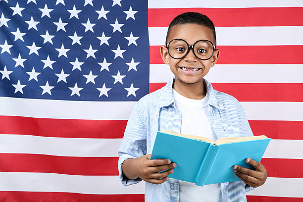 istock Cute boy with book on american flag background 2204507170