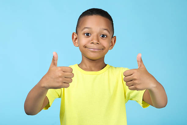 istock Cute american boy showing thumb up on blue background 2204508160
