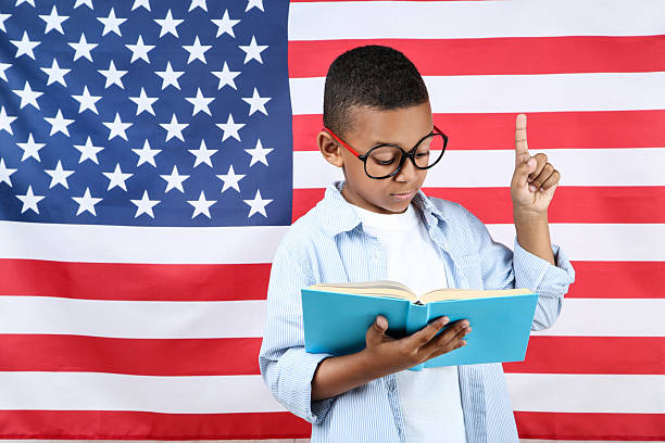 istock Cute boy with book on american flag background 2204508185