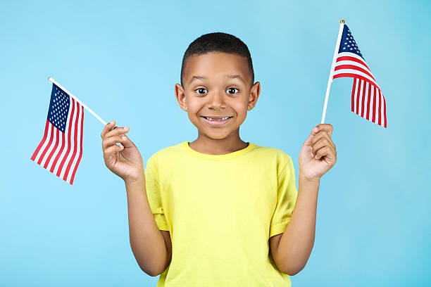 istock Cute boy with american flags on blue background 2204508454