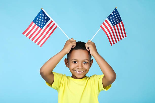 istock Cute boy with american flags on blue background 2204508695