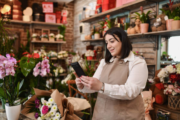 istock Beautiful Female Smiling Having Video Call While Working in Flower Shop 2204508894