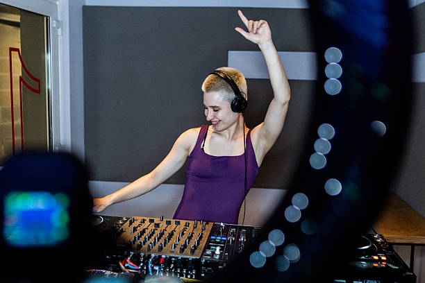 Young DJ woman using sound mixer at studio
