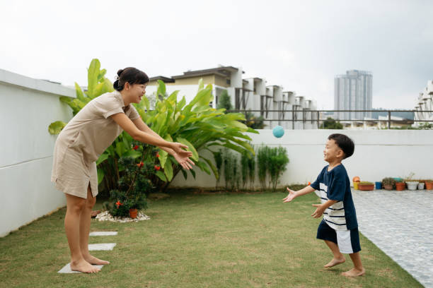 istock Asian mother and her son playing with ball in backyard 2204511069