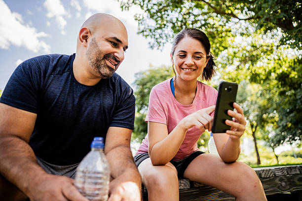 Mid adult couple using mobile phone in a public park