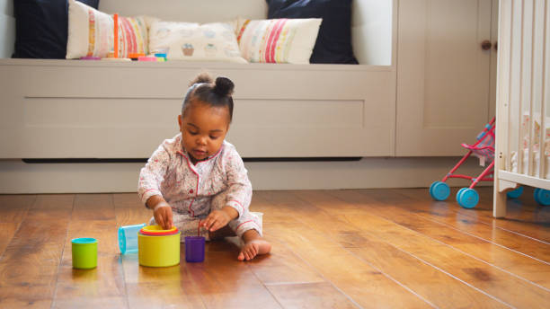 Female Toddler At Home Playing With Stacking Plastic Toy
