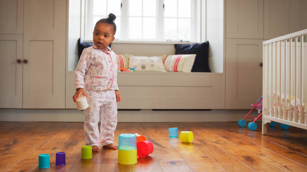 istock Standing Female Toddler At Home Playing With Stacking Plastic Toy 2204512901