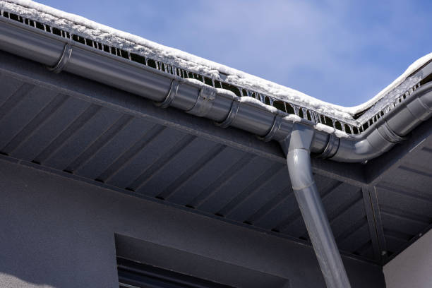 istock Modern metal gutter system with icicles and snow-covered eaves, highlighting winter conditions and roof drainage against a clear blue sky. 2204513464