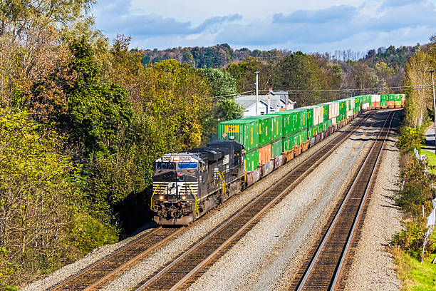 Lilly PA, USA - October 17th, 2018: Norfolk Southern container stack train passing through the rural Allegheny village of Lilly in Pennsylvania. The impressive freight train is transporting mainly green-coloured shipping containers contrasting with the black and white paint on the two locomotives.
