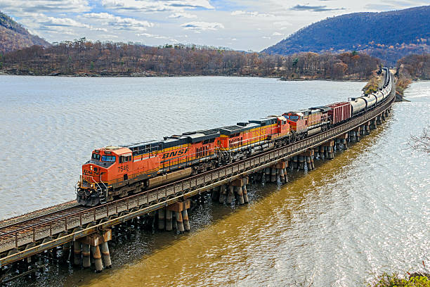 Doodletown Bight NY, USA - Nov 14, 2018: Three BNSF diesel locomotives leading a train of  empty crude oil tanks across the Doodletown Bight viaduct, crossing from Iona Island with the Hudson River in the background on a cold, bleak late Fall day.