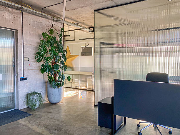 istock A modern office space with a well-lit interior, featuring a desk, decorative star element, green plant, seating, white walls, dark flooring, exposed ductwork, and an open doorway 2204516691