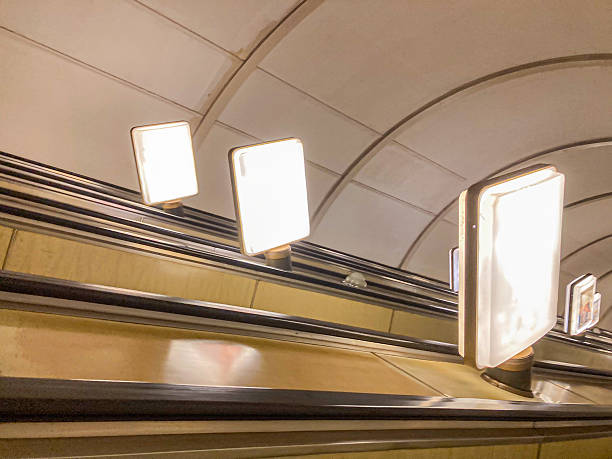 istock Image shows an upward moving escalator with safety instructionadvertisement frames on the handrail, taken at an angle suggesting a wide-angle lens effect or distortion No people visible 2204516709