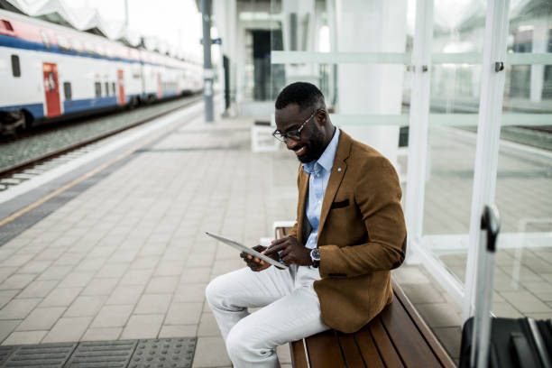 istock Happy black businessman waiting for train on railway station. 2204517099