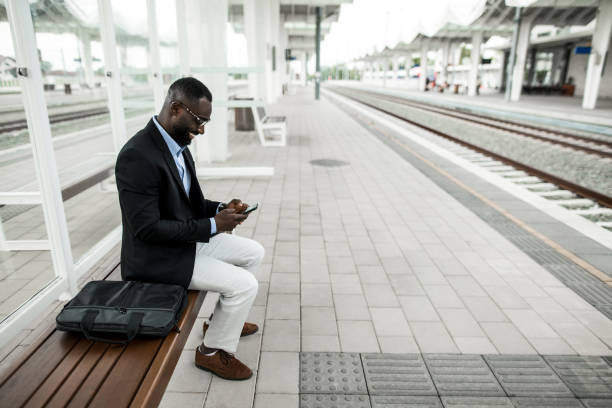 istock Happy black businessman waiting for train on railway station. 2204517468