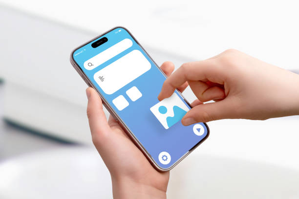 istock Close-up of hand holding smartphone, placing picture image box on app interface, concept of drag-and-drop UI design and mobile application development 2204517513