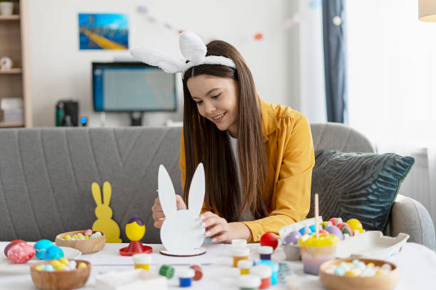 istock Young woman painting easter decorations at home 2204521045