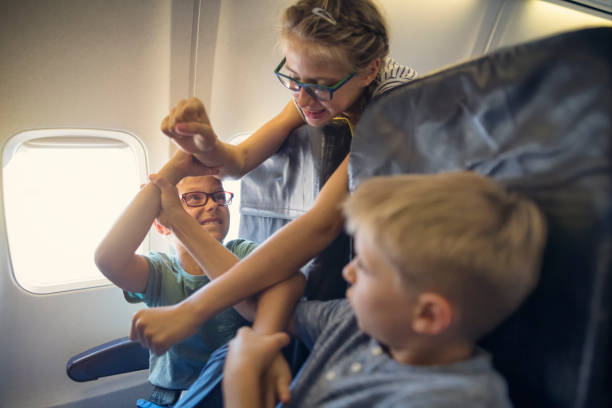 istock Three naughty kids travelling by plane, fighting and making noise 2204521407