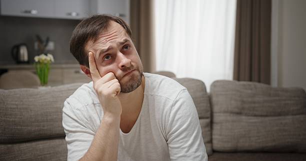 A Thoughtful Man Deep in Contemplation While Seated in a Modern and Cozy Living Room Setting