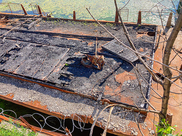 istock Image shows a scene of destruction with a severely damaged structure, likely a building or infrastructure, with an irregular hole in the upper portion, indicating fire damage and partial collapse Th 2204522174