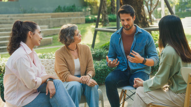 Diverse group people engaging in supportive group therapy session, sharing personal stories and advice to promote mental health and recovery in park. Mental health community concept.
