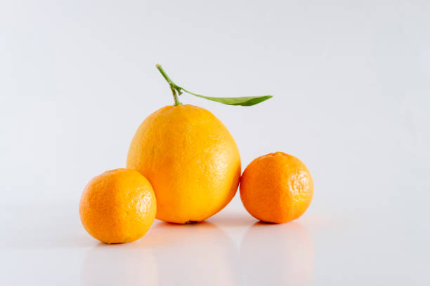 Vibrant orange and several tangerines with attached leaf sits on a white background, showcasing its freshness and natural beauty, perfect for health, food, and lifestyle themes