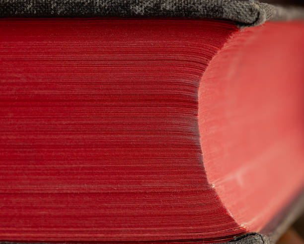 A close-up of a thick, deep red book with tightly bound pages and a textured cover. The vibrant red hue conveys depth and knowledge, vintage