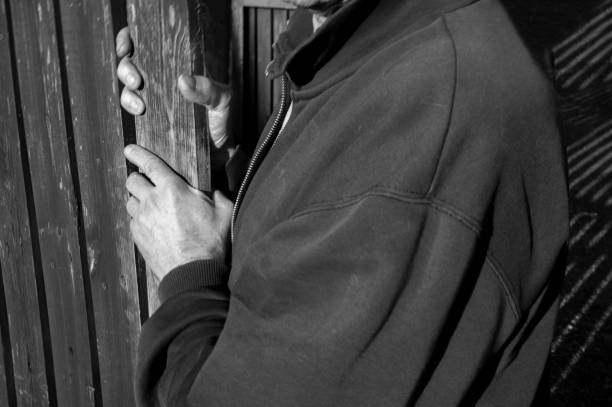 a man quitely opening a gate in wooden fence, in black white