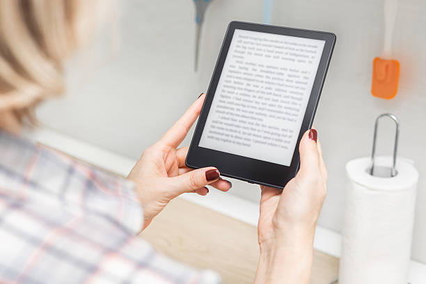 istock woman reading e-book in kitchen at home 2204532631