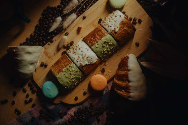 Delicious pastries and coffee beans on wooden board with macarons