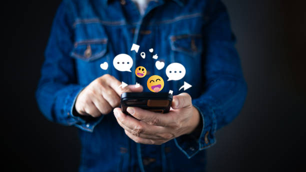 istock A person in a denim jacket interacts with a smartphone, surrounded by floating emojis, chat bubbles, hearts, and icons representing social engagement and network connectivity in the digital world. 2204533463