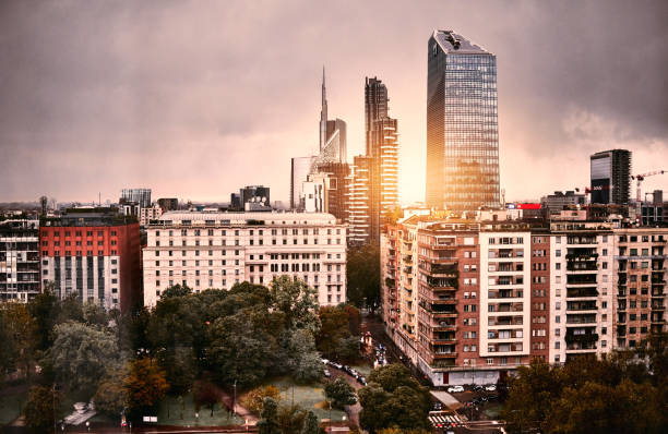 Milan, Italy city landscape A vibrant urban skyline at sunset, with modern skyscrapers and dramatic clouds reflecting warm golden light.