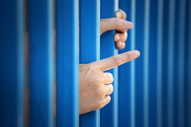 Hand Reaching Through Blue Bars Symbolizing Confinement and Hope