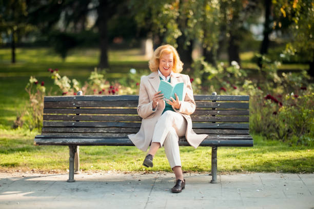 istock Senior Woman Enjoying a Book While Relaxing Outdoors on a Bench in Autumn 2204540689