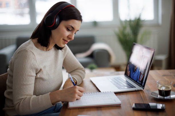istock Young woman improving her skills through online education, taking notes attentively 2204544173