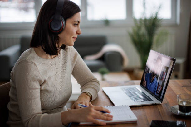 Woman in headphones attending an online course and making notes