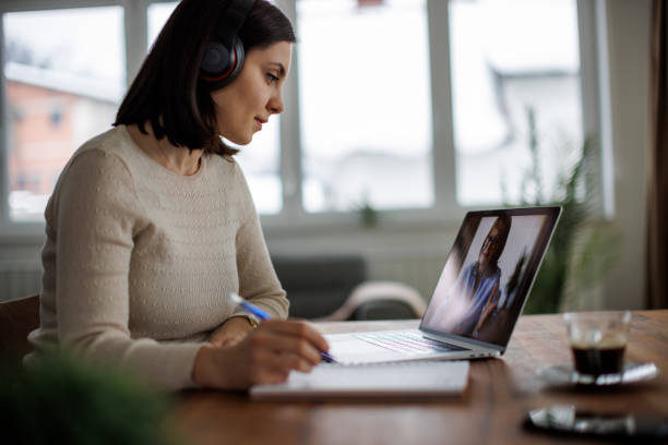 istock Female adult student watching an online lecture and taking notes at home 2204544280