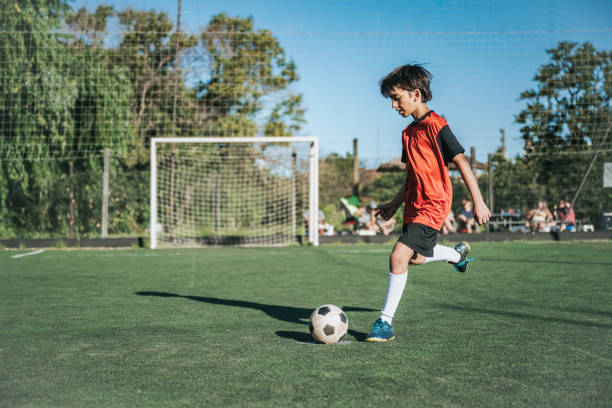 istock soccer boy kicking the ball on field 2204544405